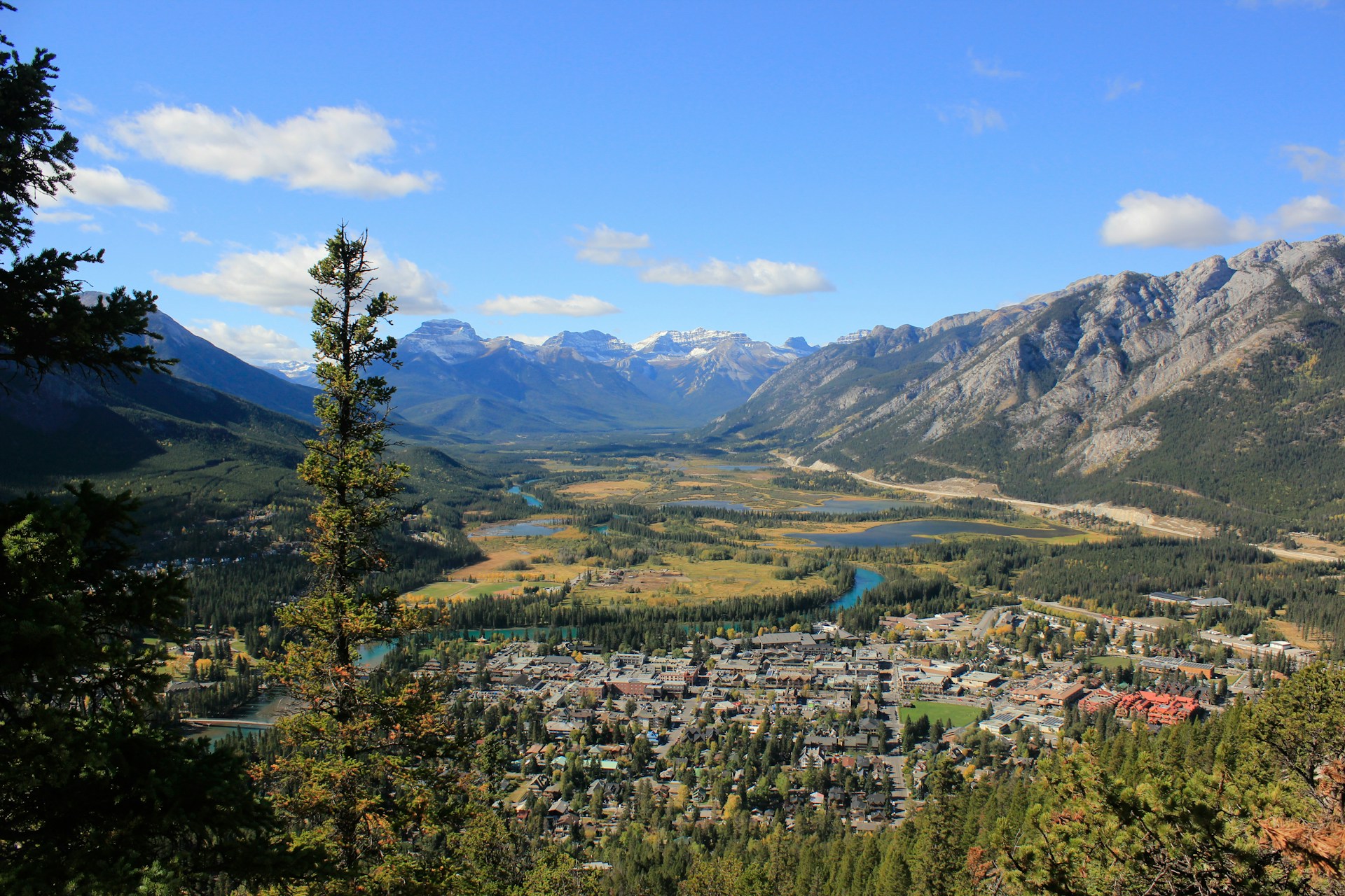 Banff townsite seen from above on a clear early-autumn day, with the Bow River winding through the valley and mountains beyond