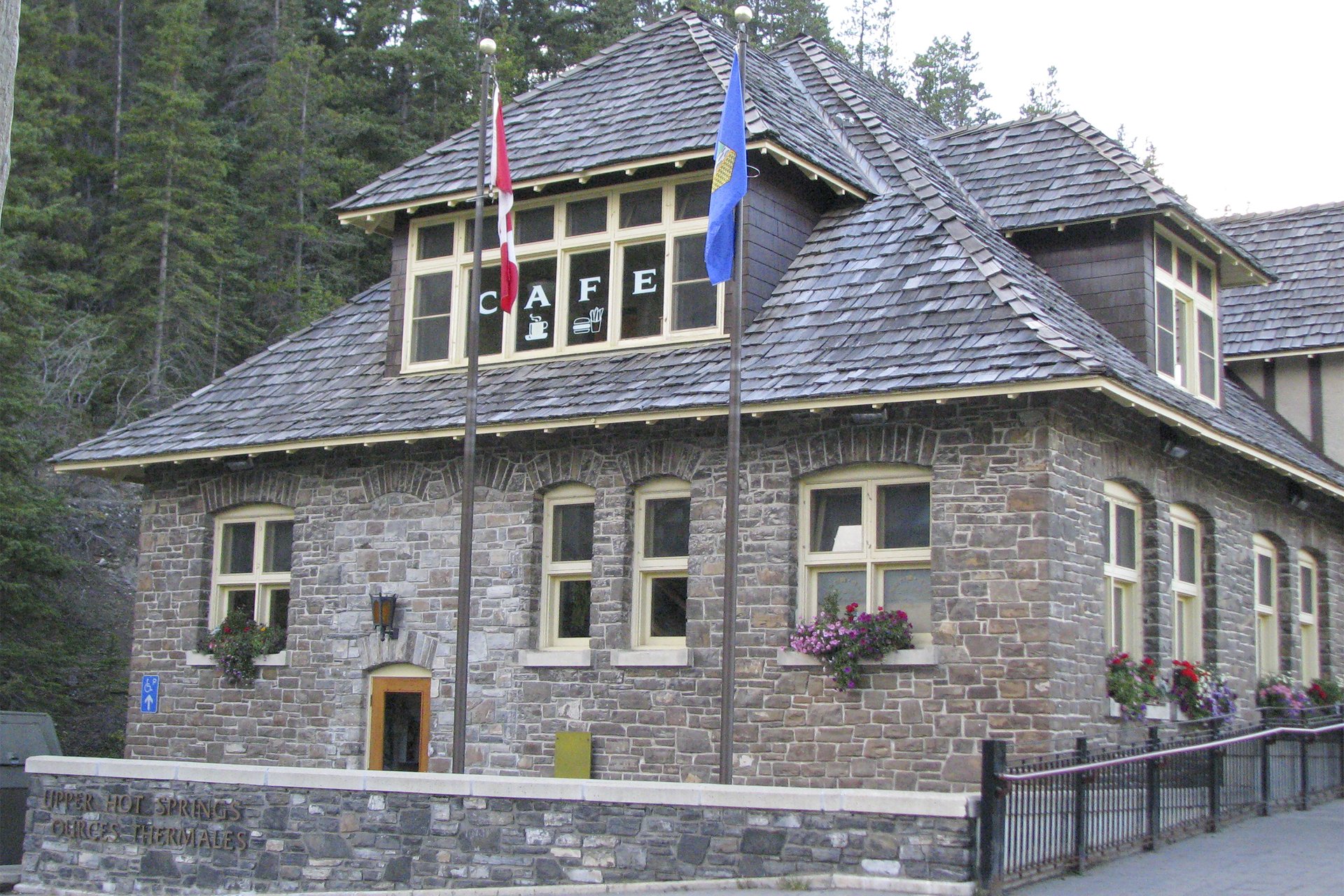 The stone bathhouse at the Banff Upper Hot Springs, with flags out front and café lettering in the upper windows