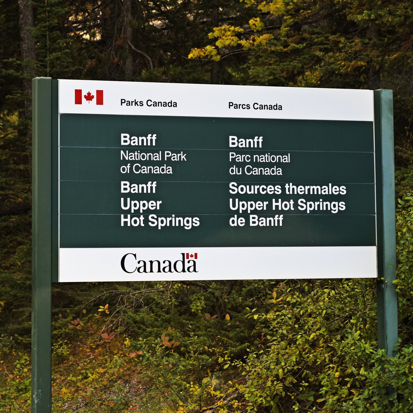 Parks Canada sign reading Banff Upper Hot Springs in English and French, set against autumn trees