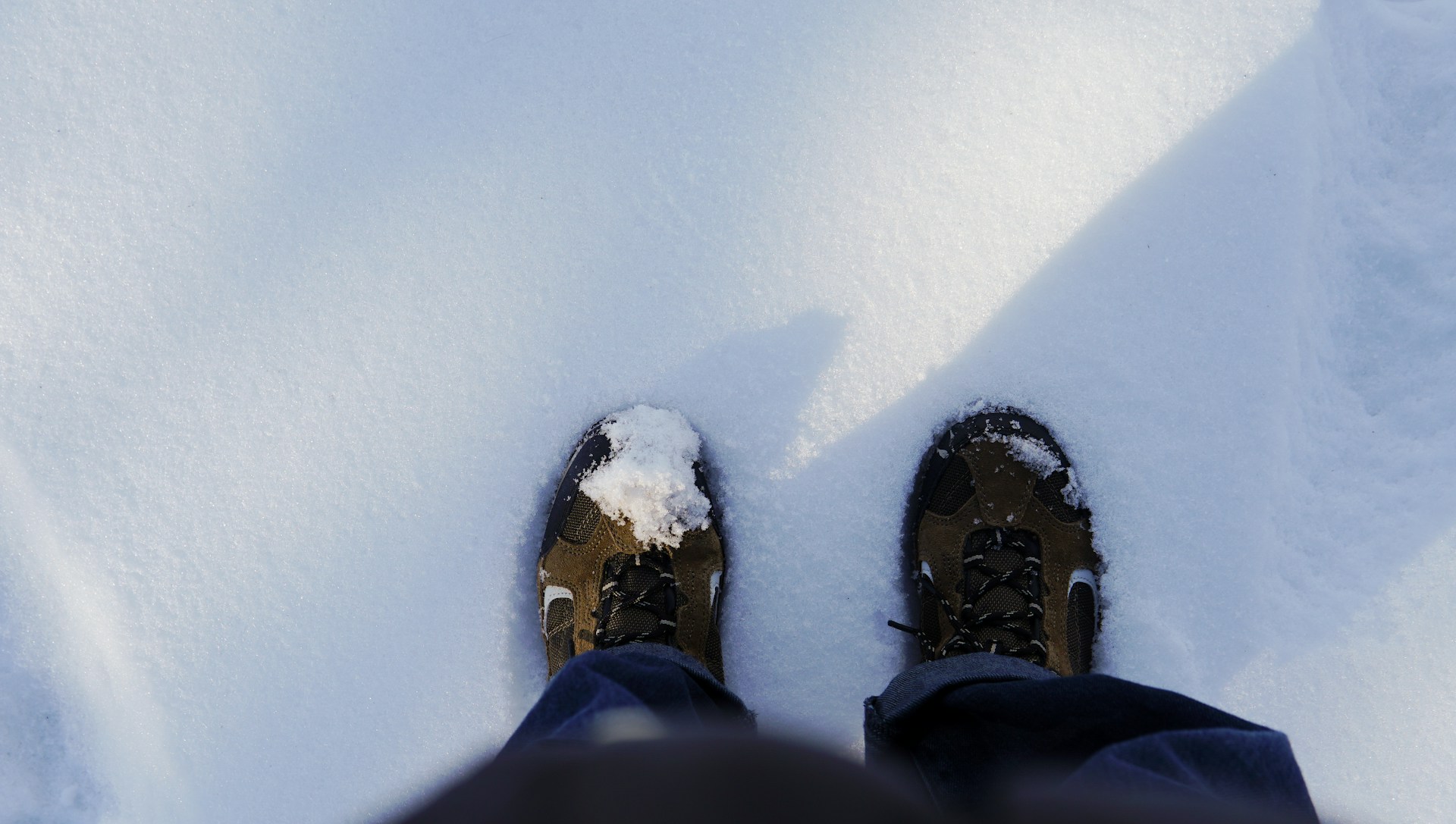 Looking down at a pair of winter boots sunk into deep fresh snow