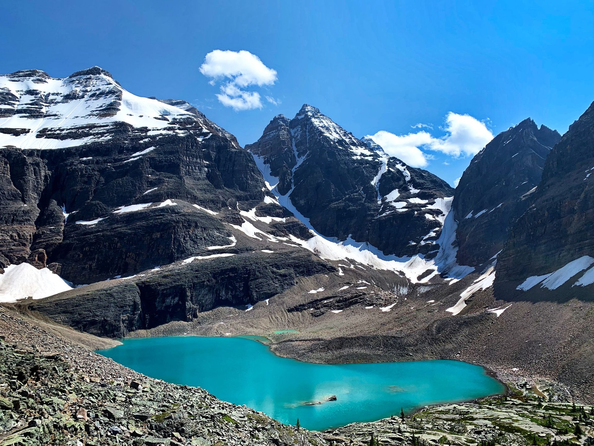Turquoise Lake Oesa in a rocky basin below snow-streaked peaks, with boulder fields in the foreground, Yoho National Park